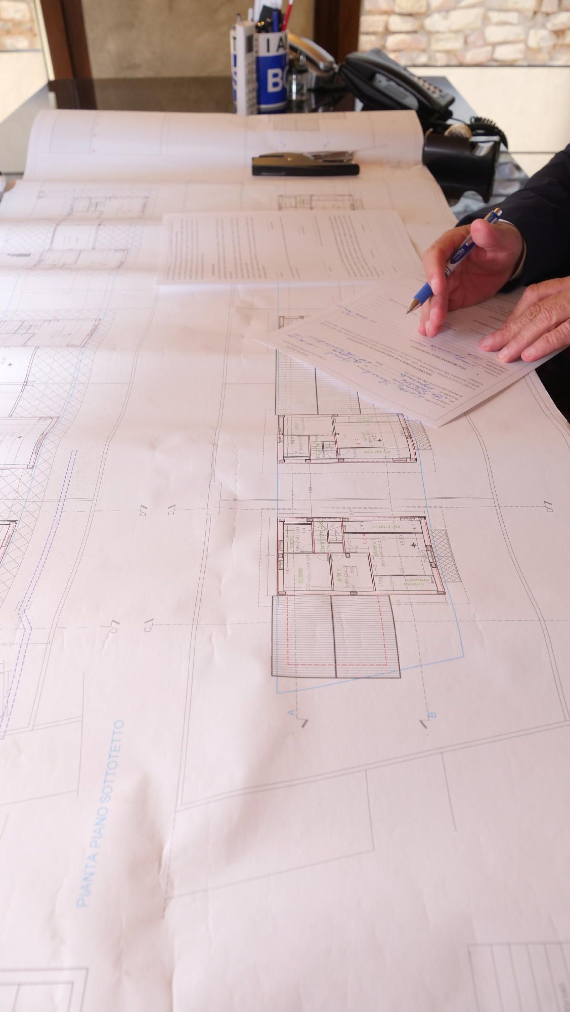 Una persona è seduta a un tavolo e guarda la planimetria di una casa.