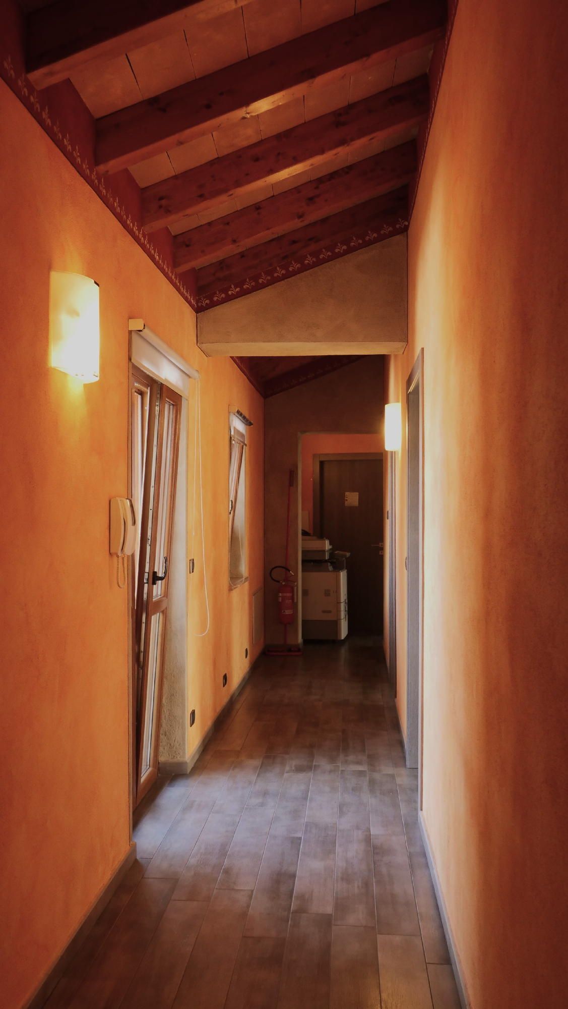 Un lungo corridoio con pareti arancioni e soffitto in legno