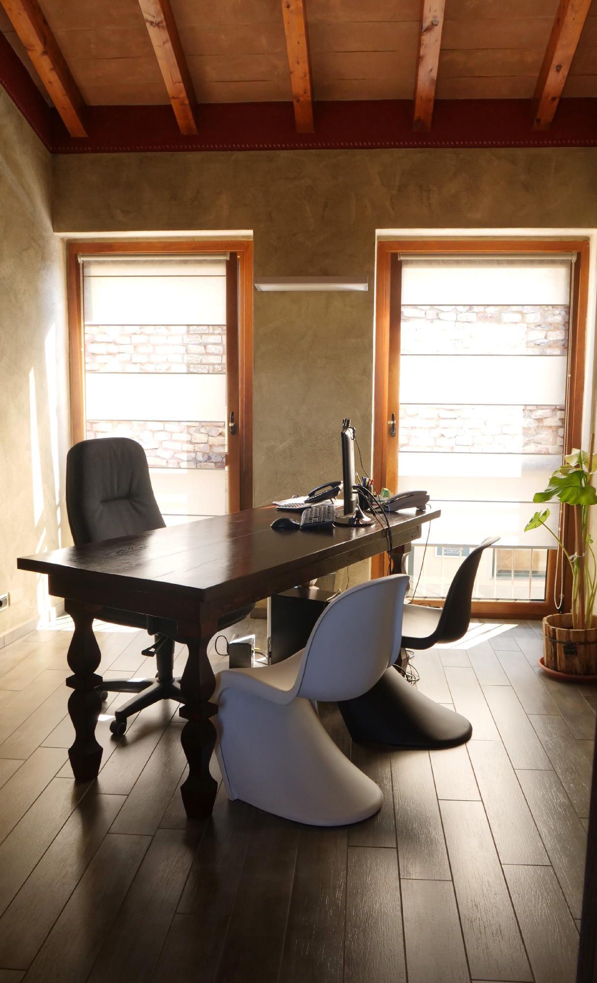 Una stanza con una scrivania, sedie e una finestra