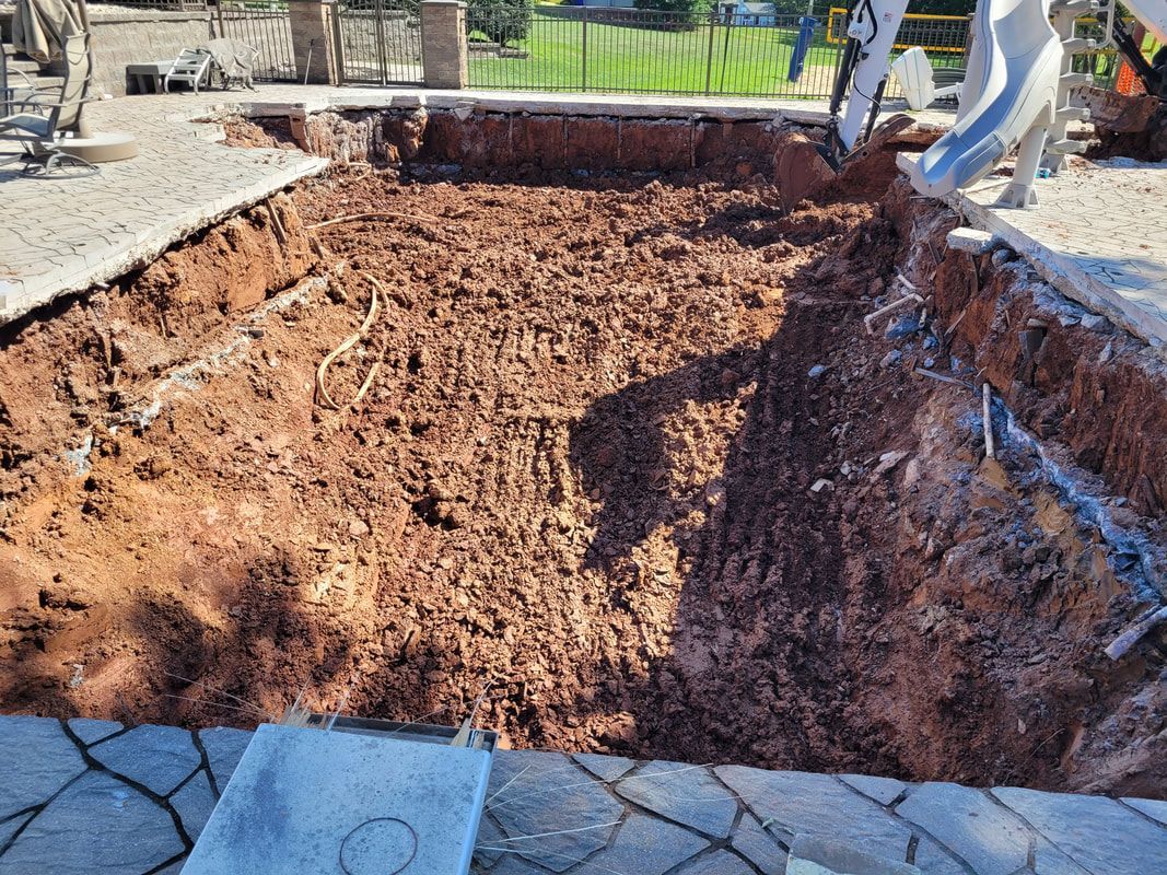 Excavated rectangular hole in the ground; dirt walls and bottom; part of a construction site.