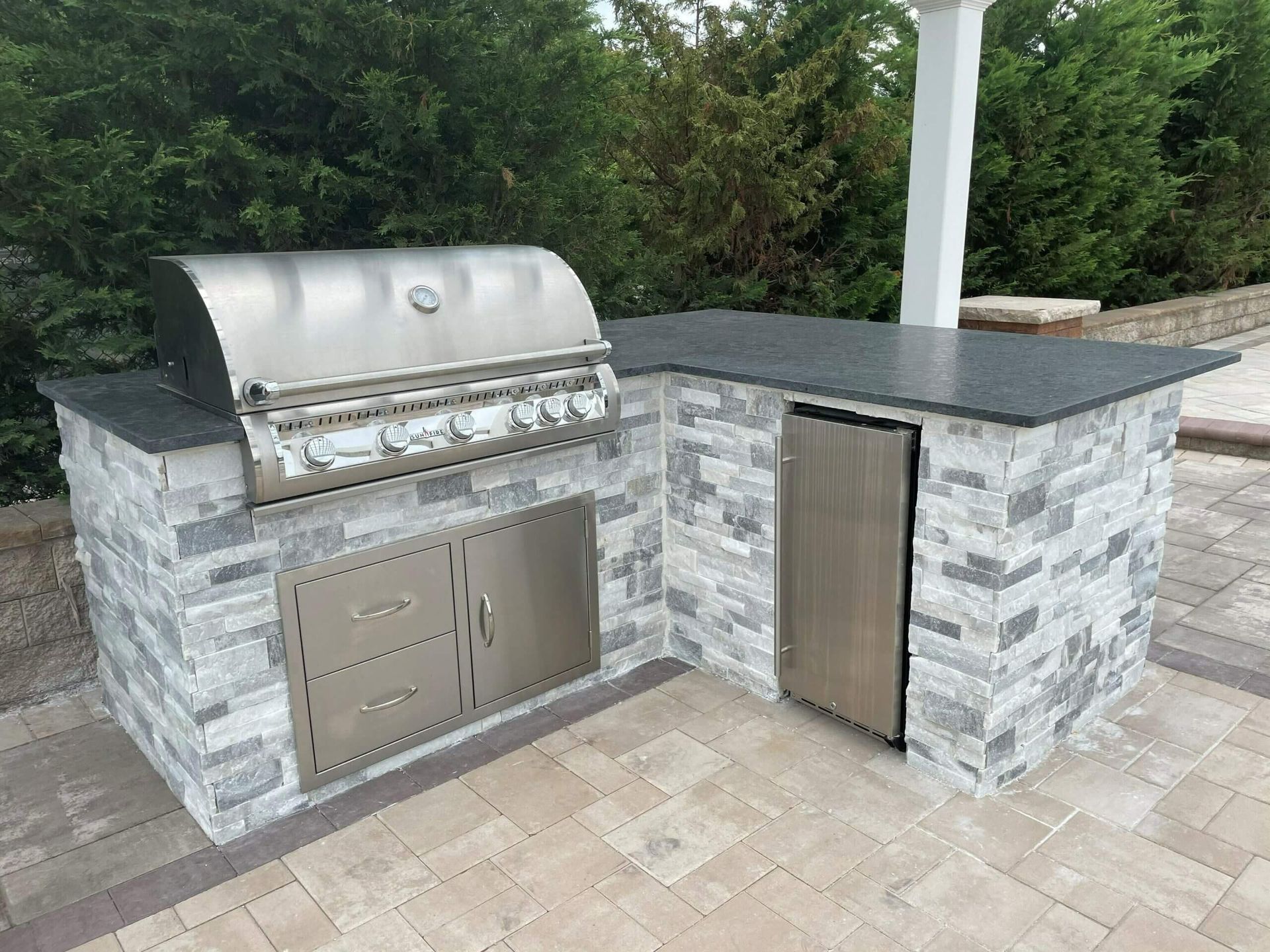 Outdoor grill and countertop with stainless steel appliances and stone facade.