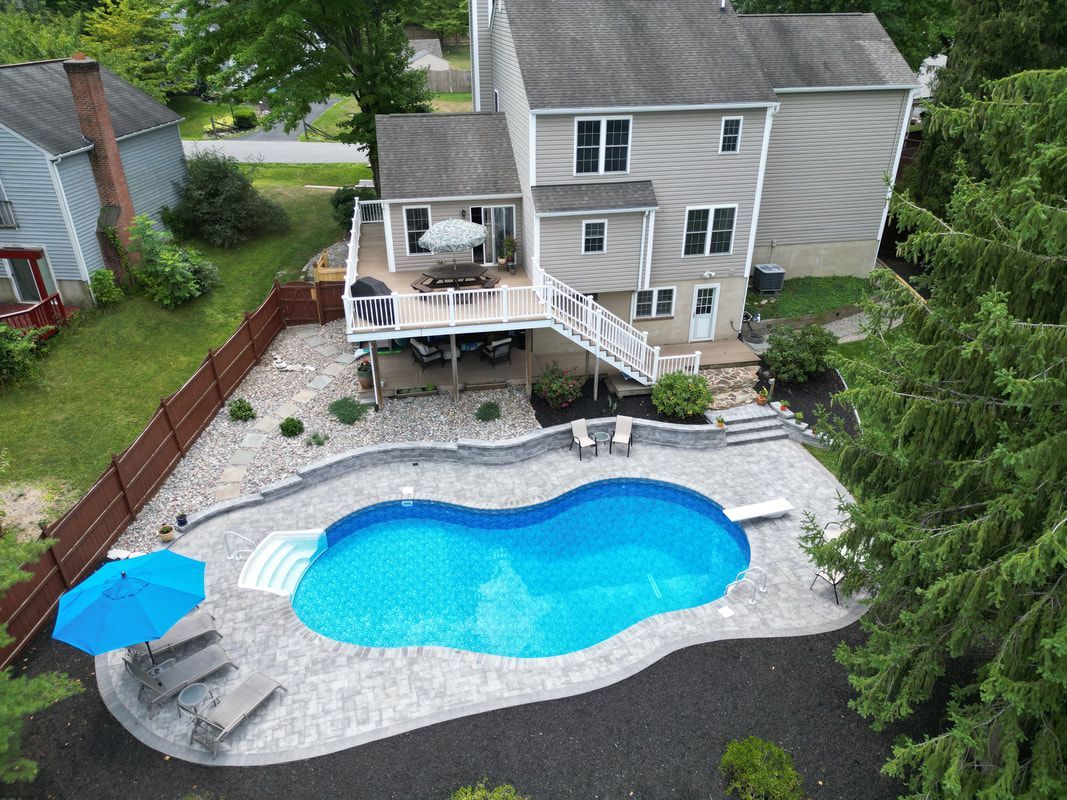 Aerial view of a house with a blue kidney-shaped pool, deck, and landscaping.