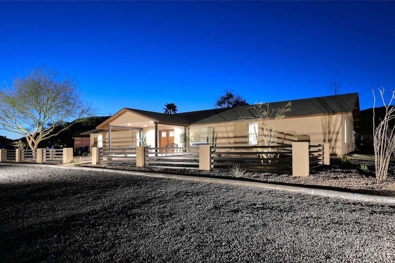 A house with a fence around it is lit up at night.