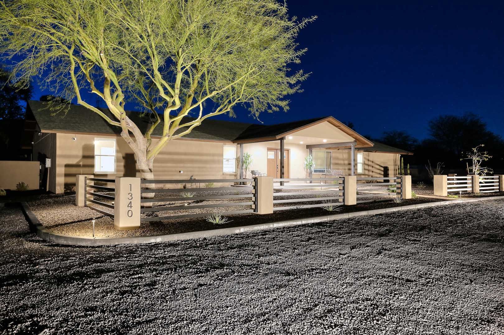 Night-Front Corner View2-min A house with a fence and a tree in front of it at night.