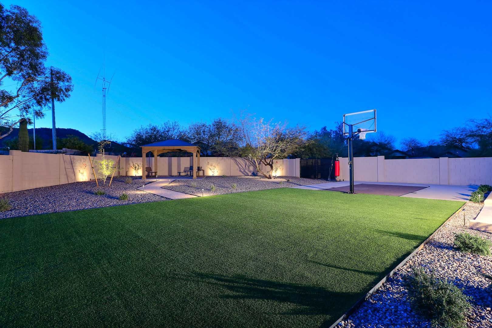 Night-Grass Area-min A backyard with a basketball hoop in the middle of it