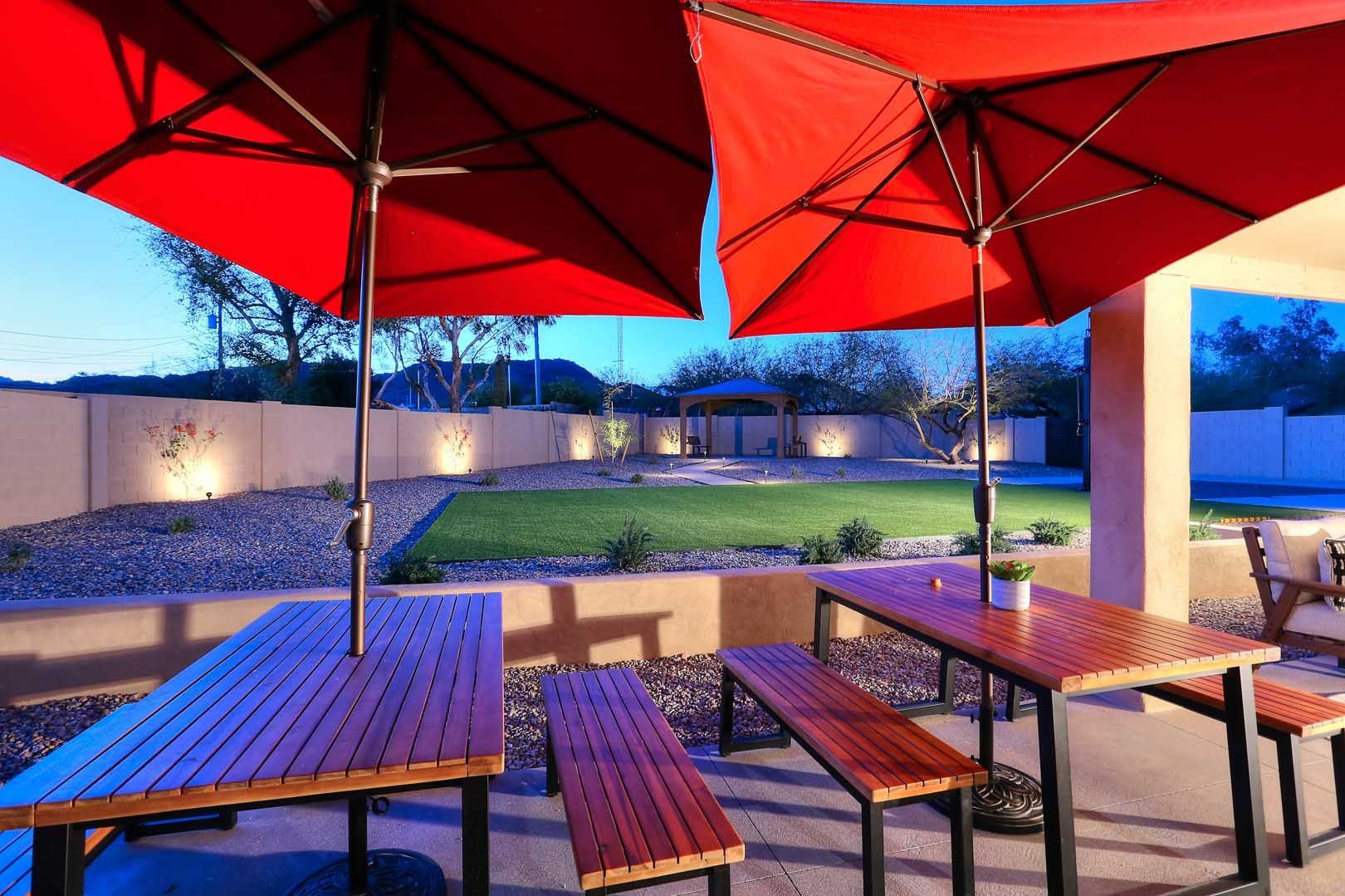 Night-Outdoor Dining Area2-min A patio with tables and benches under red umbrellas