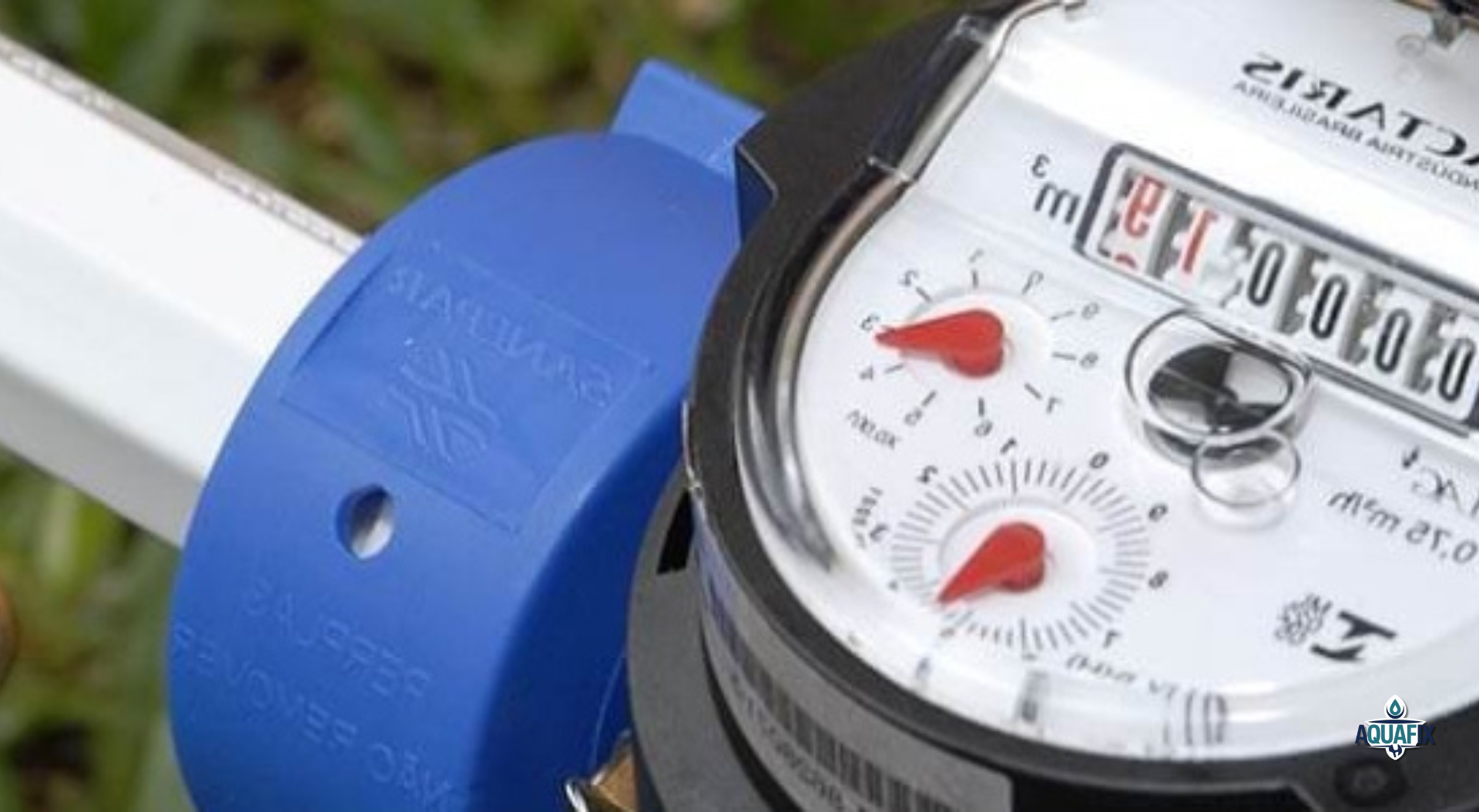 Close-up of a water meter; blue band, white pipe, black meter face with red needles, numbers showing water usage.