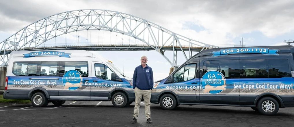 Paved road with double yellow lines, a pond with a red floating structure, and trees under a cloudy sky.