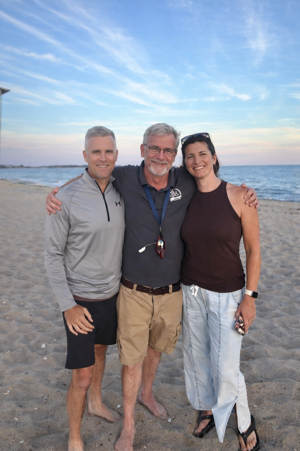 Boats moored in a harbor with a pier and buildings on the shore under a blue sky.