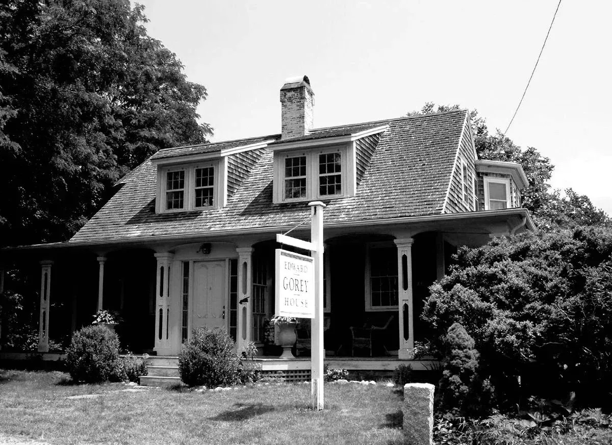 Red and white lighthouse under a clear blue sky, with a small white building to the left.