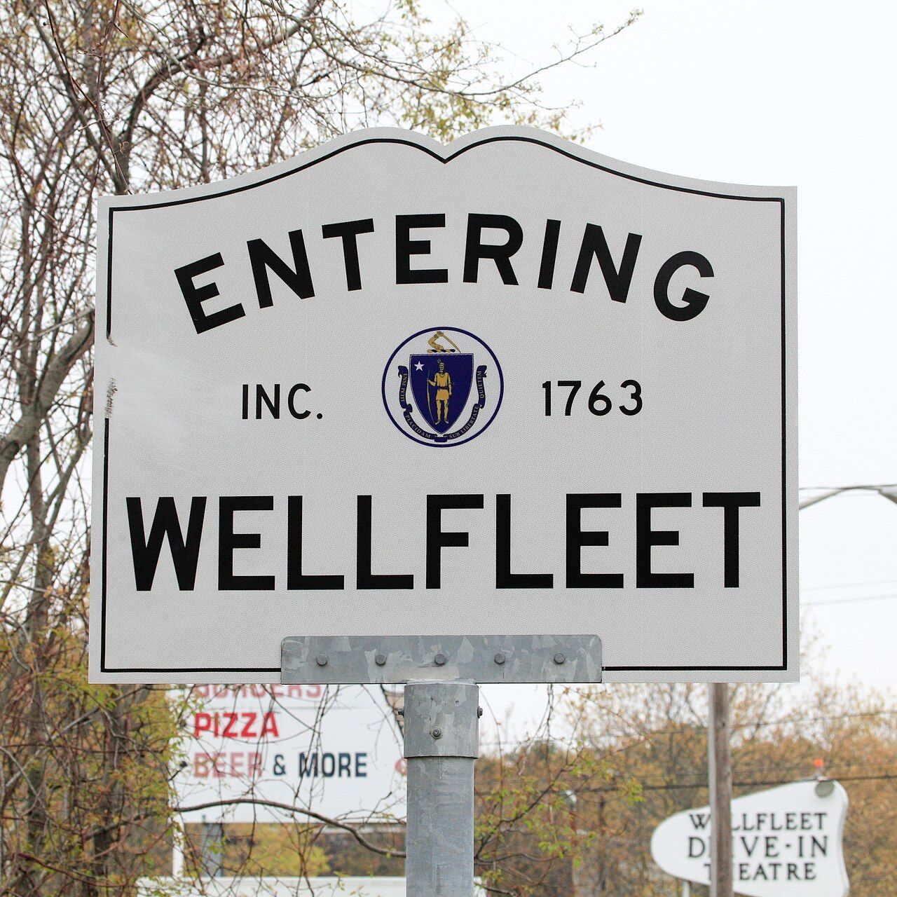 Cobblestone street lined with shops and buildings. Two people walk away.