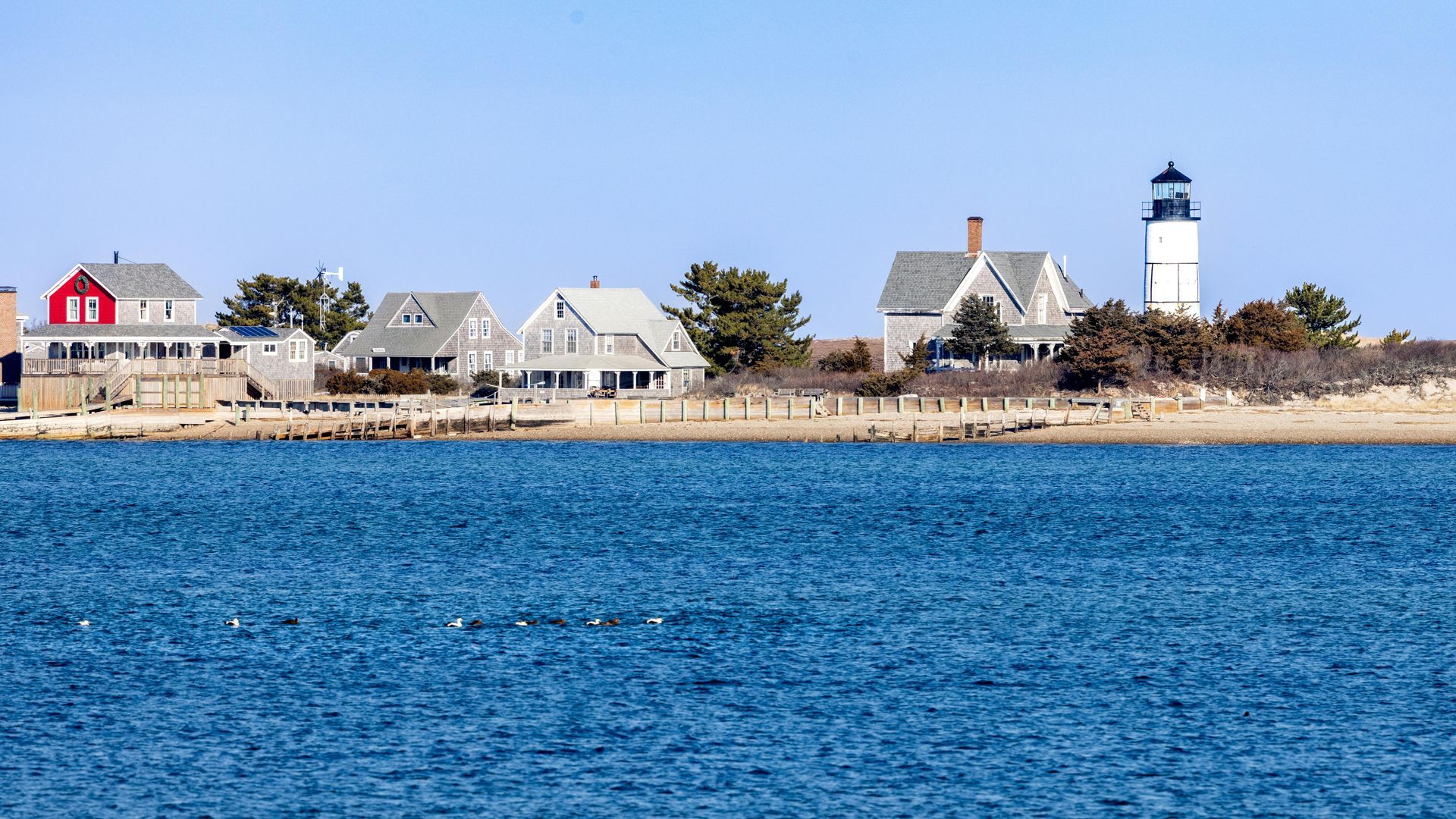 Coastal scene with houses, a lighthouse, and blue water.