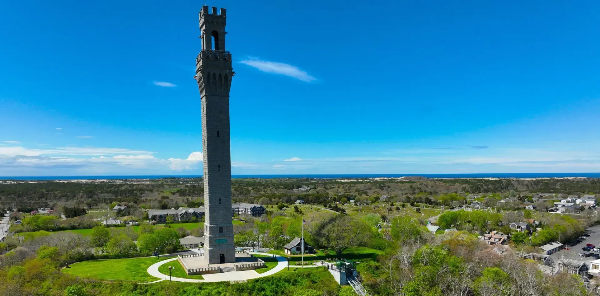Red and white lighthouse under a clear blue sky, with a small white building to the left.