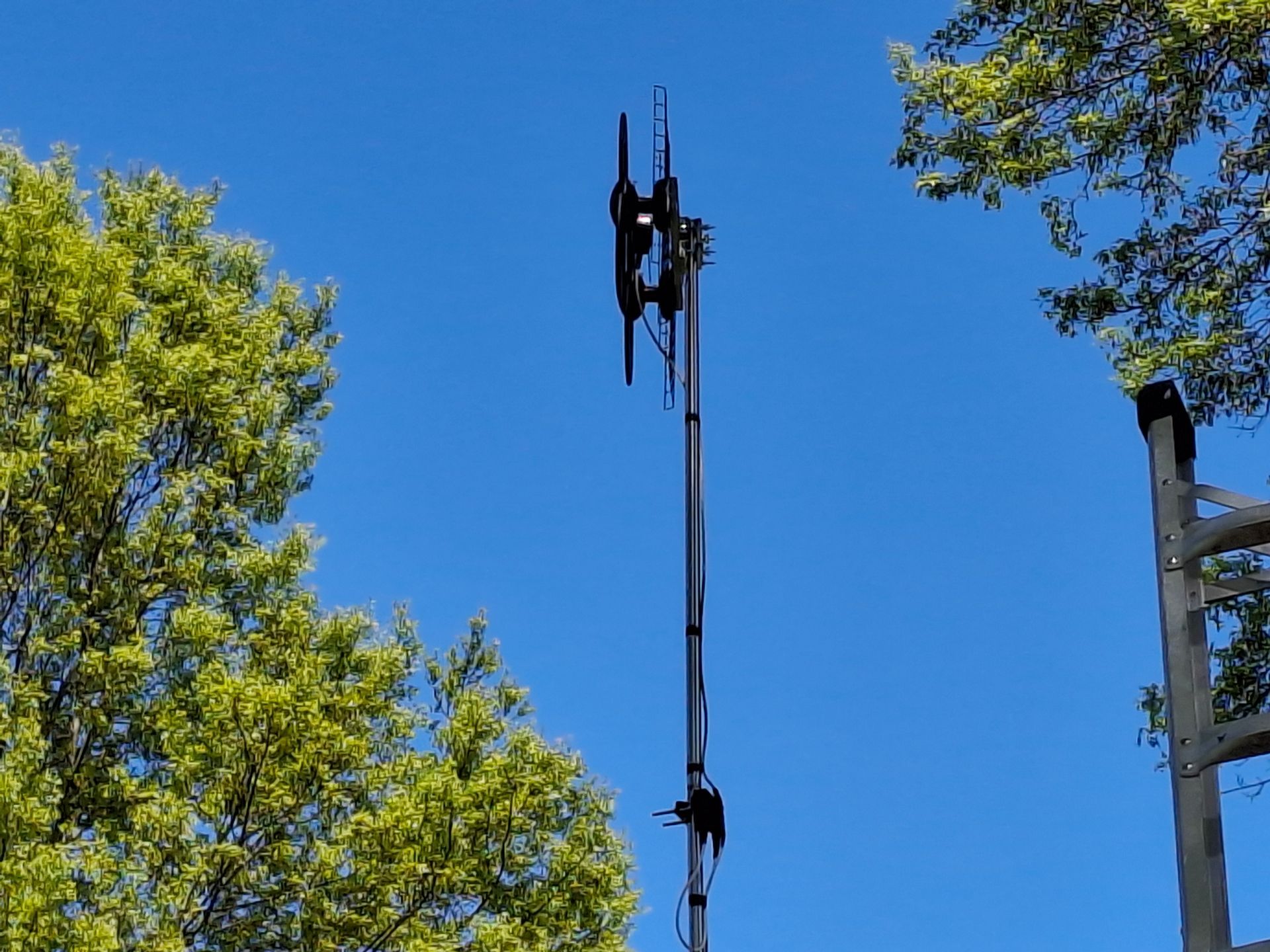 A telephone pole with a blue sky and trees in the background