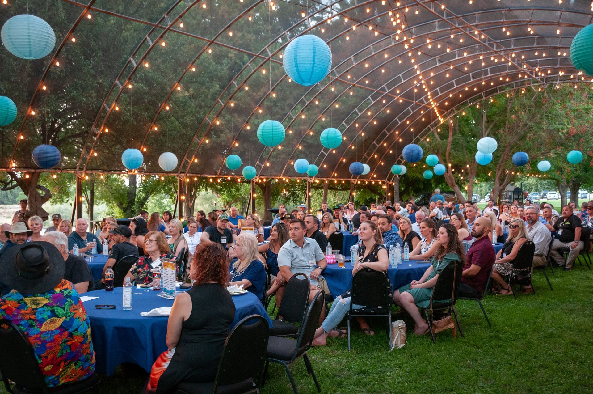 A large group of people are sitting at tables under a tent.