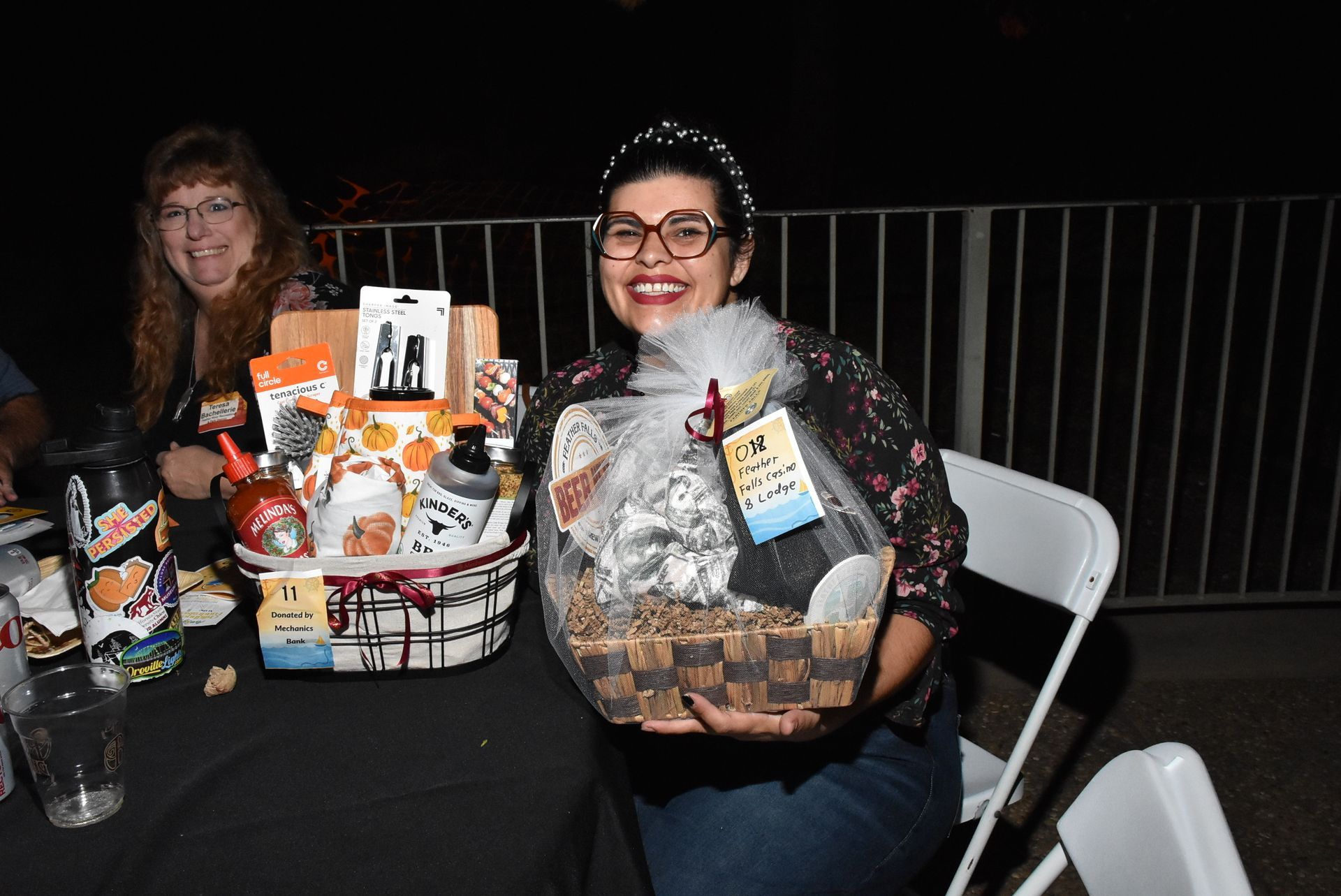 Smiling raffle winner holding a prize basket filled with sponsor-donated items at the Oroville Economic Alliance Annual BBQ.