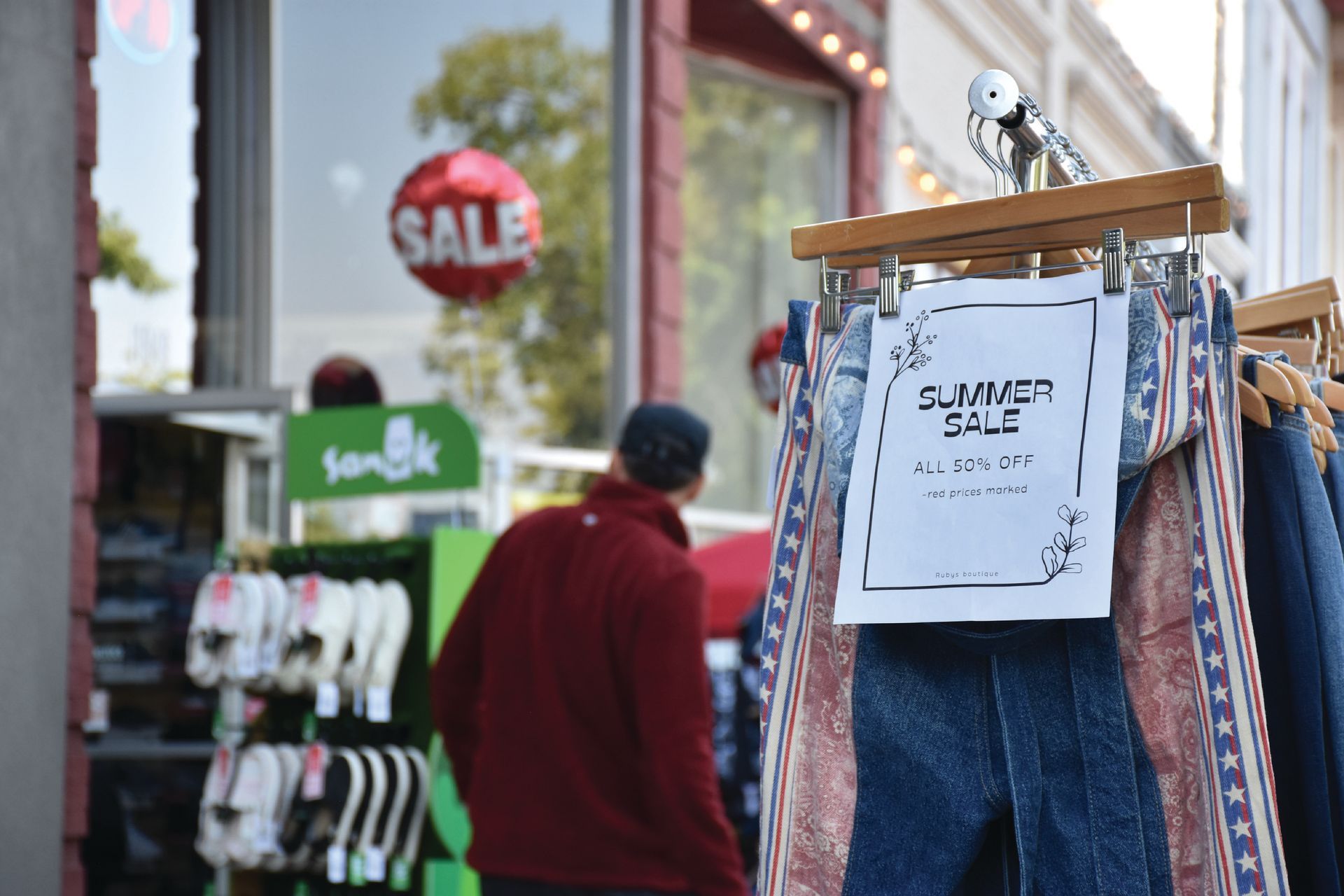 Clothing rack with a “Summer Sale – All 50% Off” sign outside a downtown boutique during the Salmon Festival.