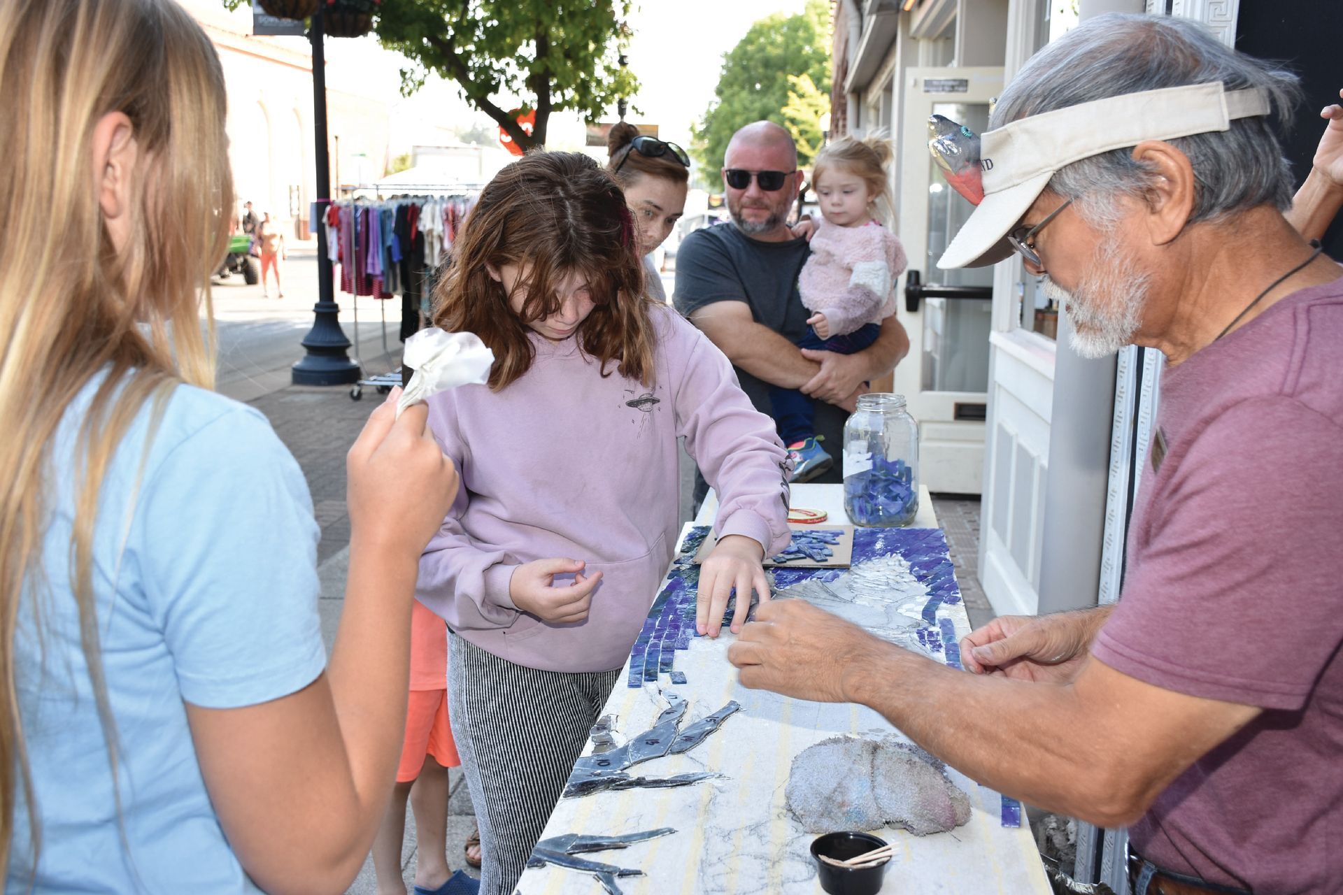 Children and families participate in a hands-on mosaic art activity with colorful tiles at the Salmon Festival.