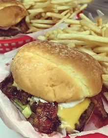 A hamburger and french fries in a basket on a table.