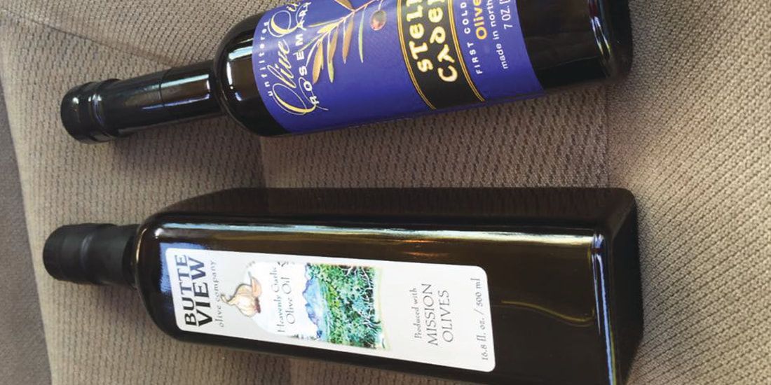 Two bottles of olive oil are sitting on a couch