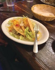 A plate of food with a fork on a wooden table.