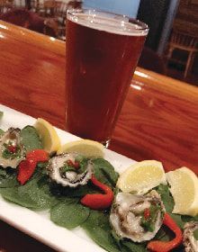 A plate of food and a glass of beer on a table.