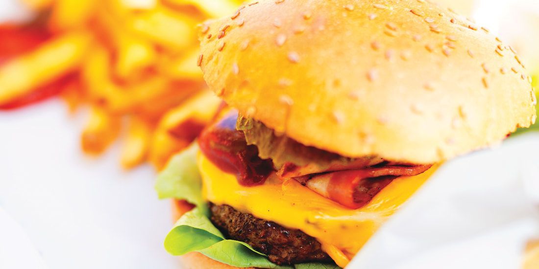 A close up of a hamburger and french fries on a white plate.