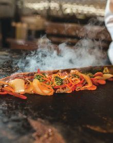 A person is cooking vegetables on a grill.