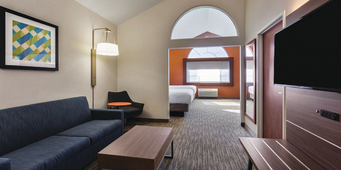A hotel room with a couch , table , and television.