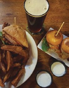 A table topped with plates of food and a glass of beer.