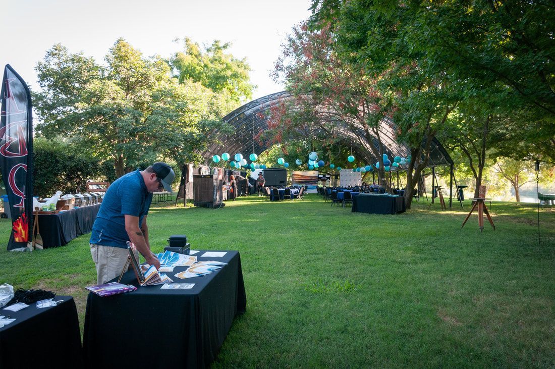 A man is standing in front of a table in a park.