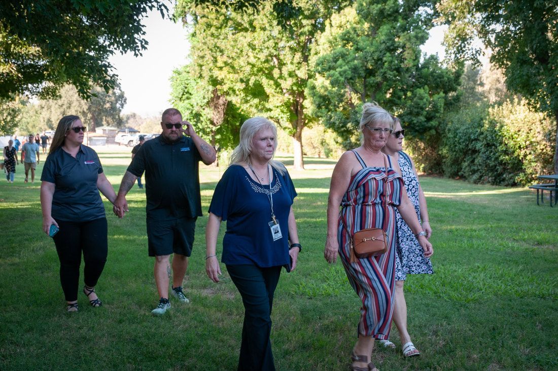 A group of people are walking through a park holding hands.