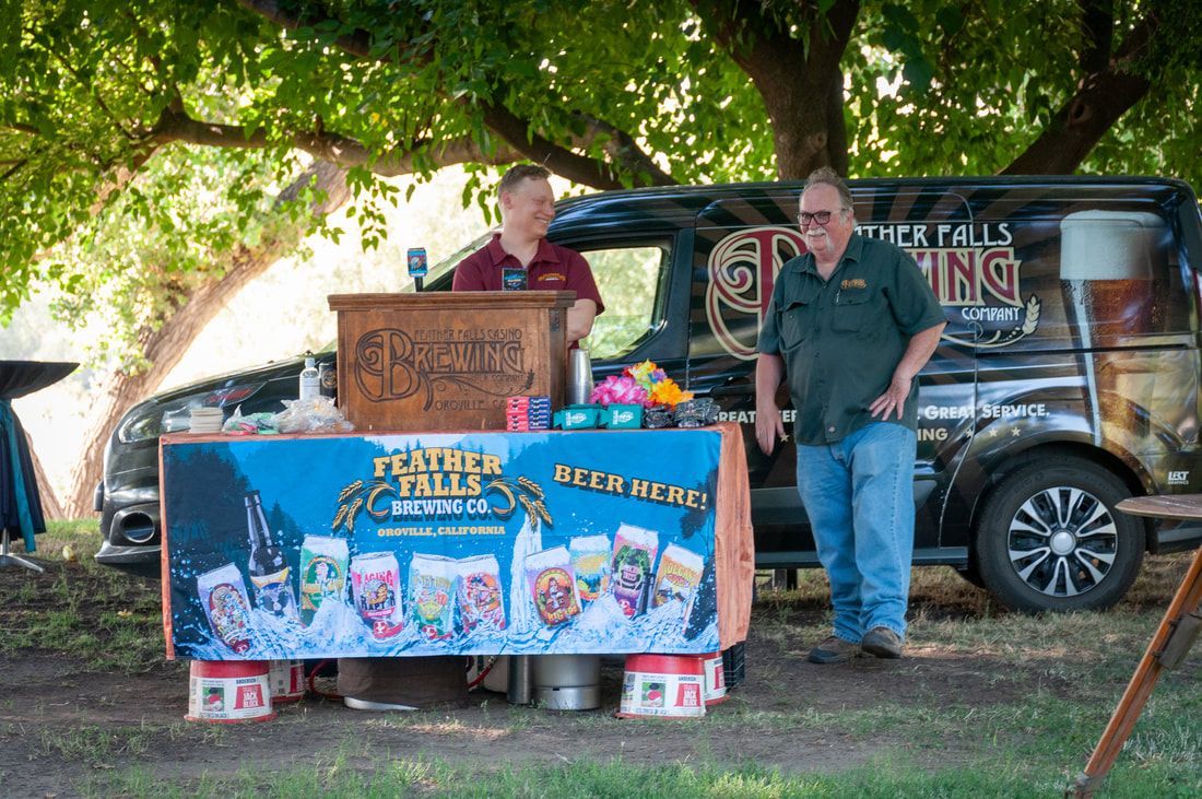 Two men are standing in front of a table with a sign that says ' beer ' on it.