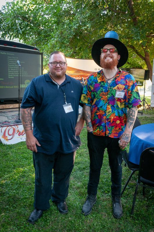 Two men are standing next to each other in the grass.