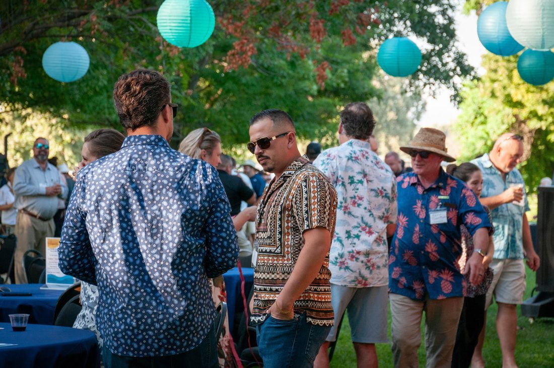 A group of people are standing in a park talking to each other.