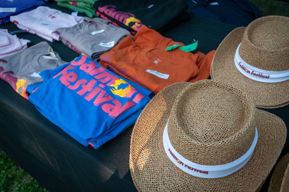 A table with shirts and hats including one that says festival