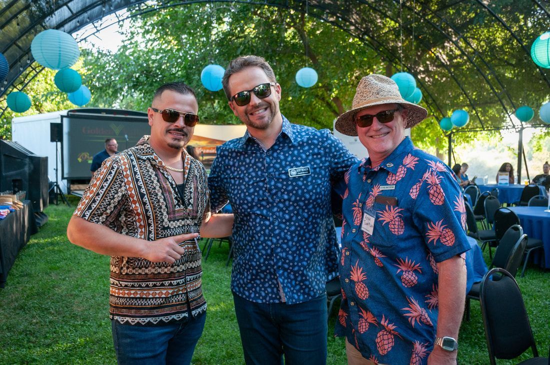 Three men are posing for a picture in front of a tent.