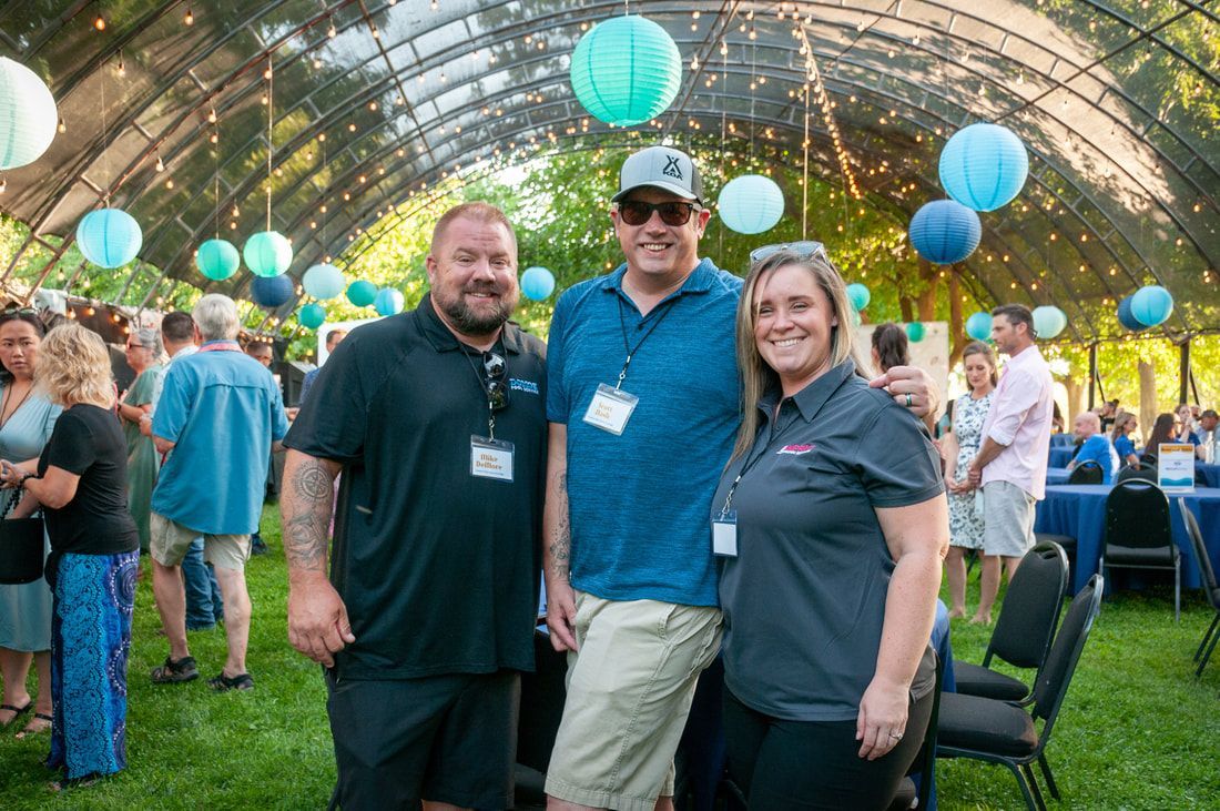 A group of people are posing for a picture under a tent at a party.