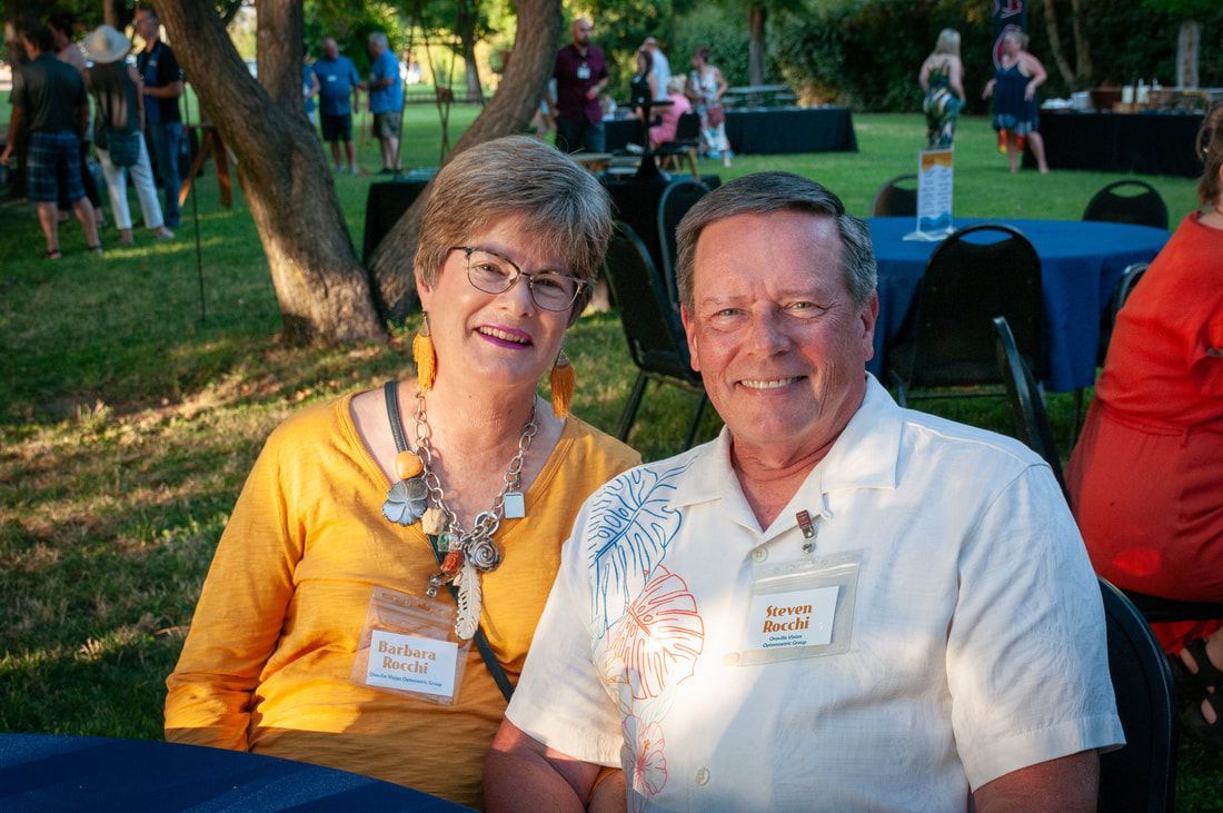 A man and a woman are posing for a picture while sitting at a table.