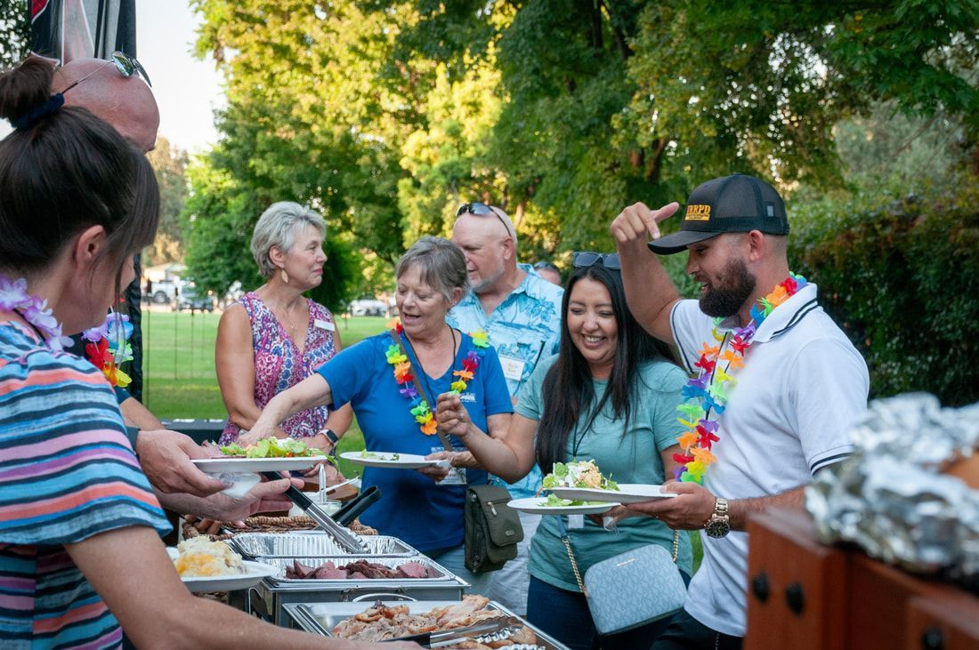 A group of people are standing around a table eating food.