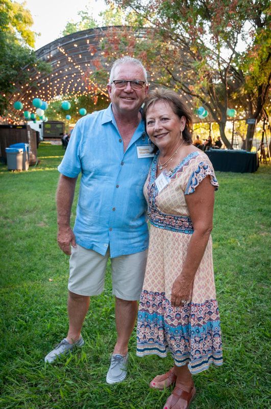 A man and a woman are standing next to each other on a lush green field.
