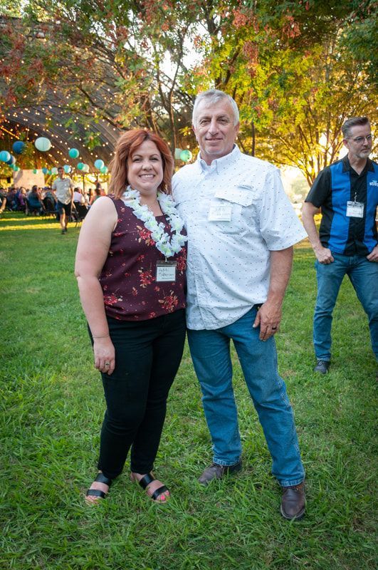 A man and a woman are posing for a picture in the grass.