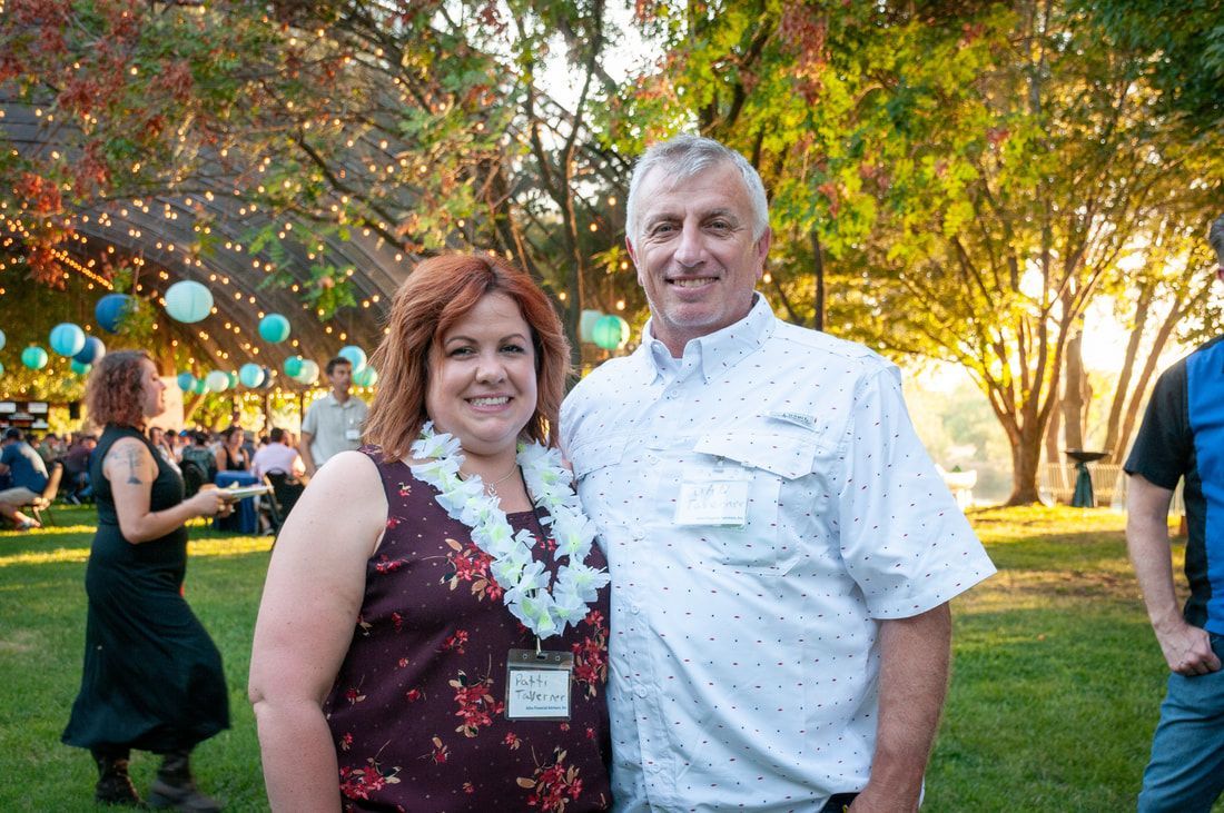 A man and a woman are posing for a picture in a park.