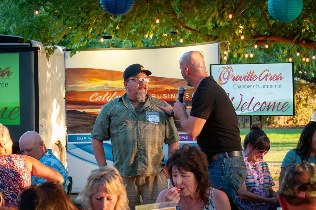 Two men are standing in front of a sign that says welcome
