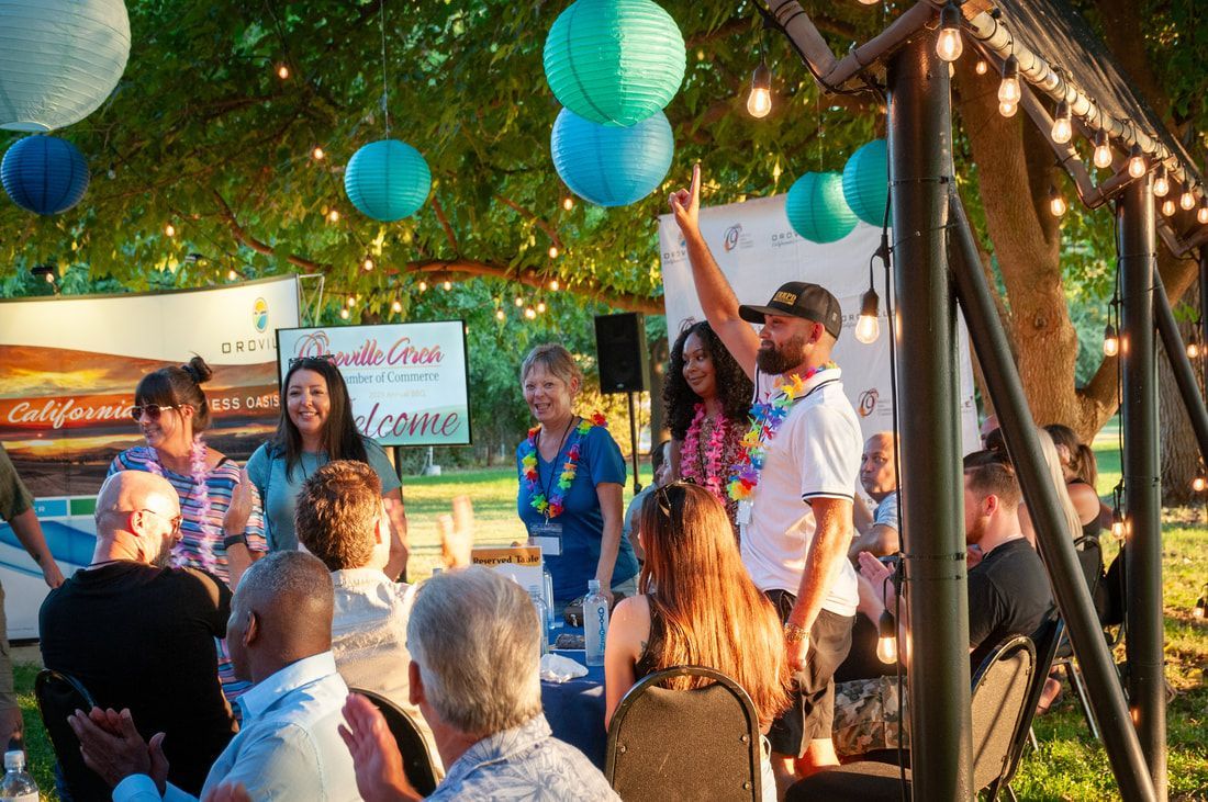 A group of people are sitting under a tree at a party.