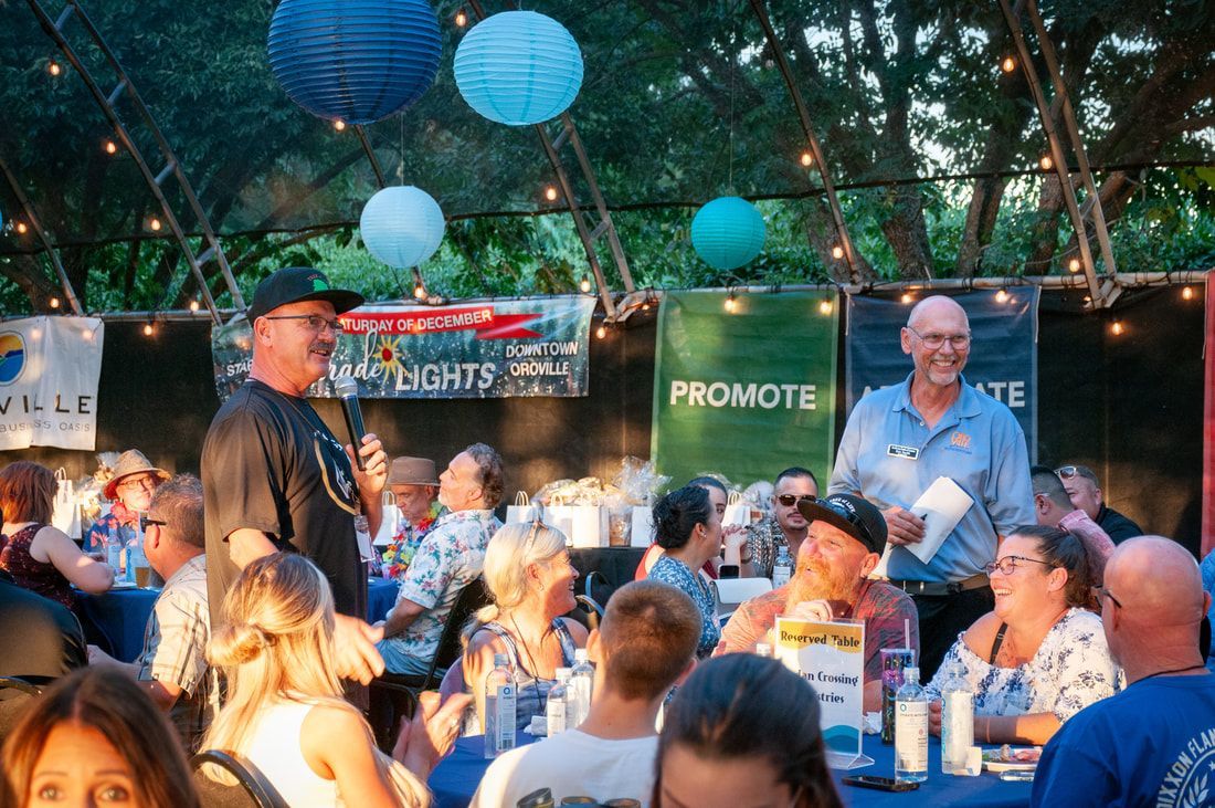 A group of people are sitting at tables under a tent.