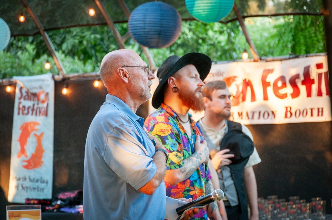 Three men are standing in front of a sign that says festival.