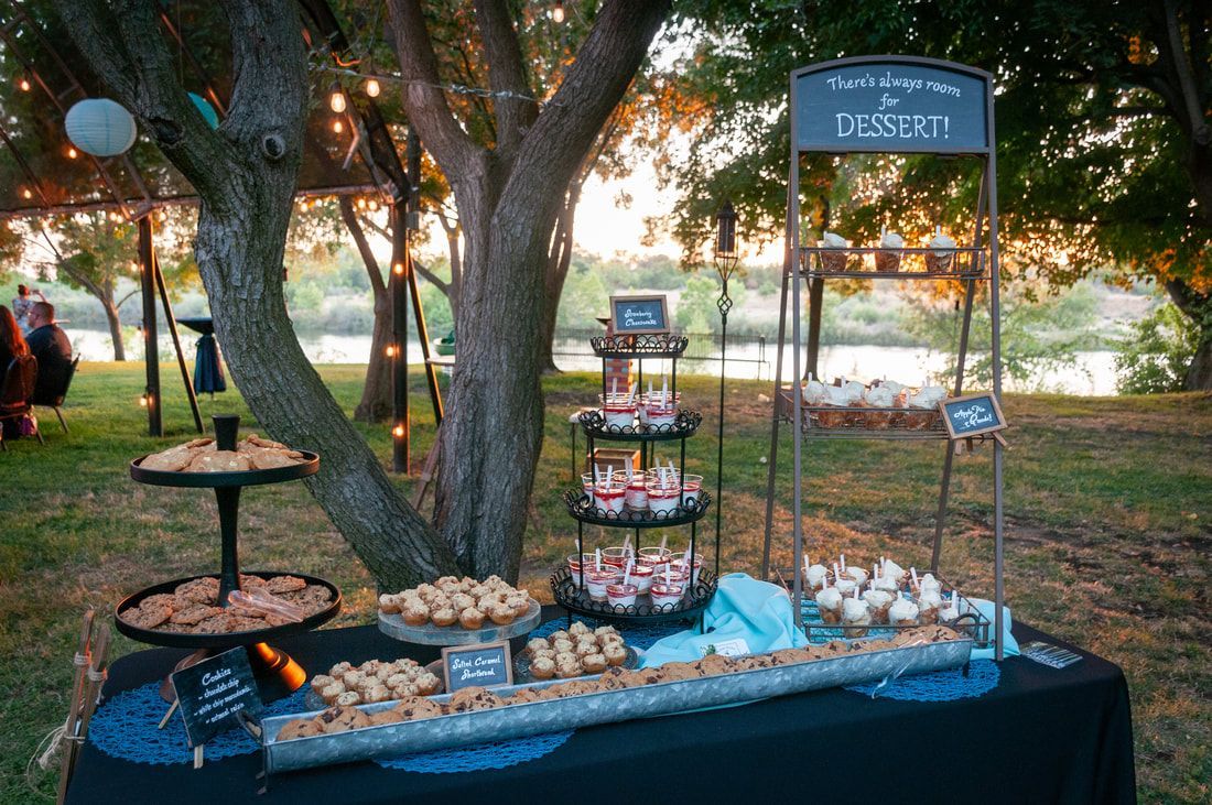 A table with a variety of desserts on it under a tree.