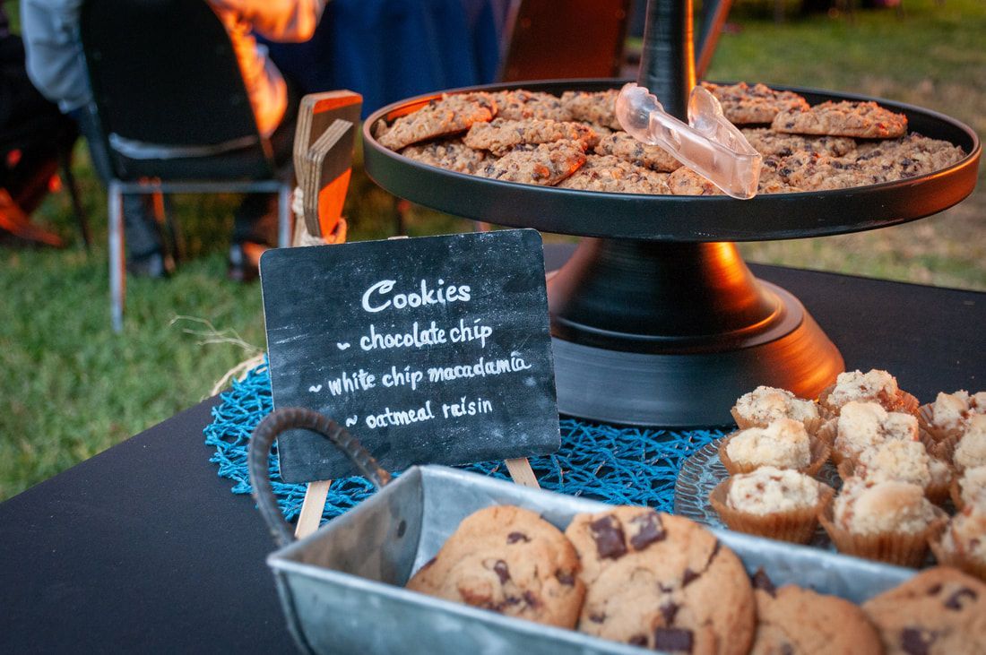 A tray of cookies and muffins on a table with a sign that says `` cookies ''.