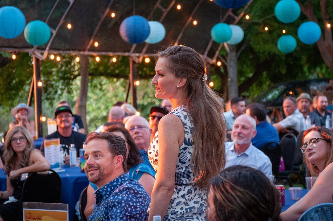 A woman is standing in front of a crowd of people at a party.